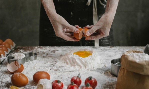 パン生地を作ろうとして卵を割っているシェフの手元